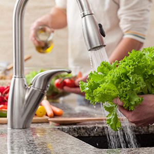 washing fresh lettuce under a faucet