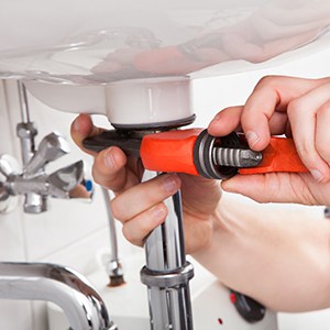 A plumber fixing a sink in bathroom