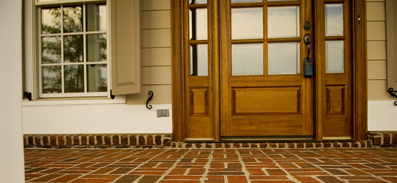 close up of a brick front porch with a front door and side window