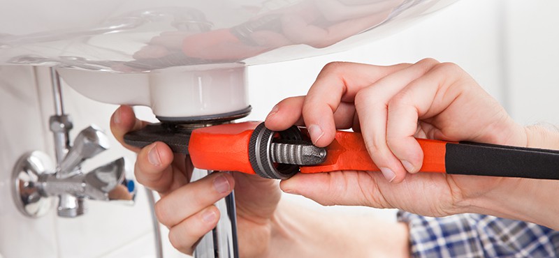 A plumber fixing a sink in bathroom