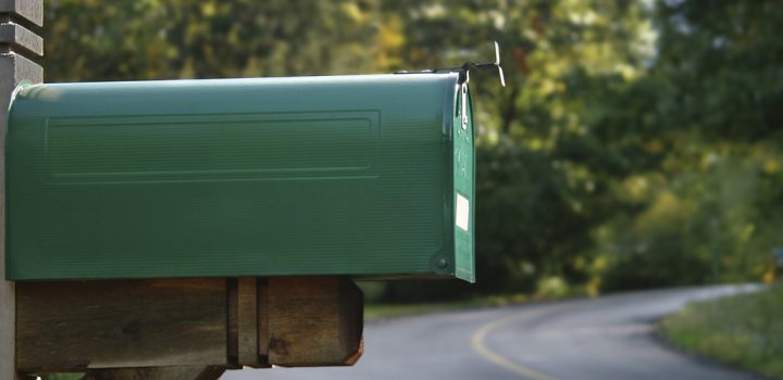 A green mailbox in a rural neighborhood.