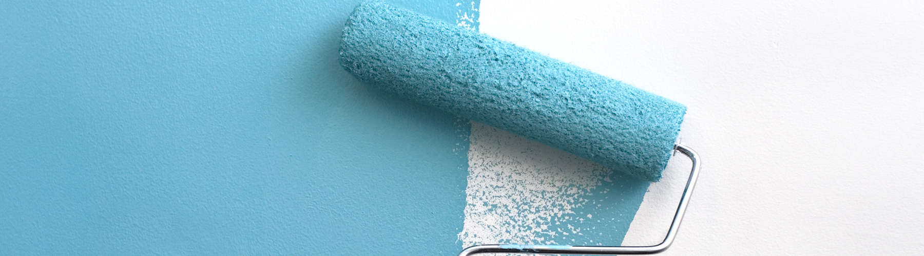A paint roller covered in teal blue paint, painting over an interior white wall.