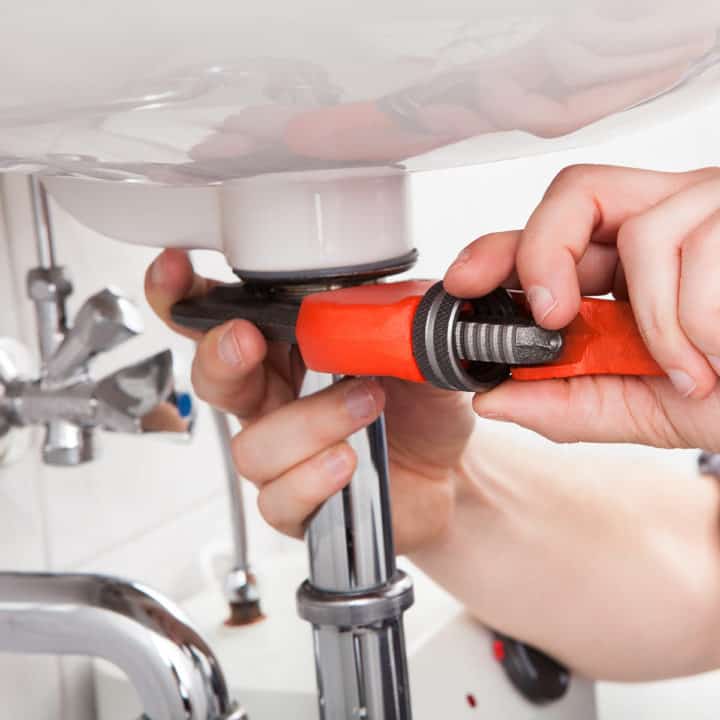 Portrait of male plumber fixing a sink in bathroom