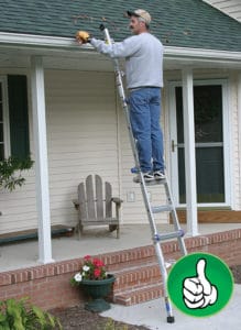 man on ladder cleaning gutters in front of house