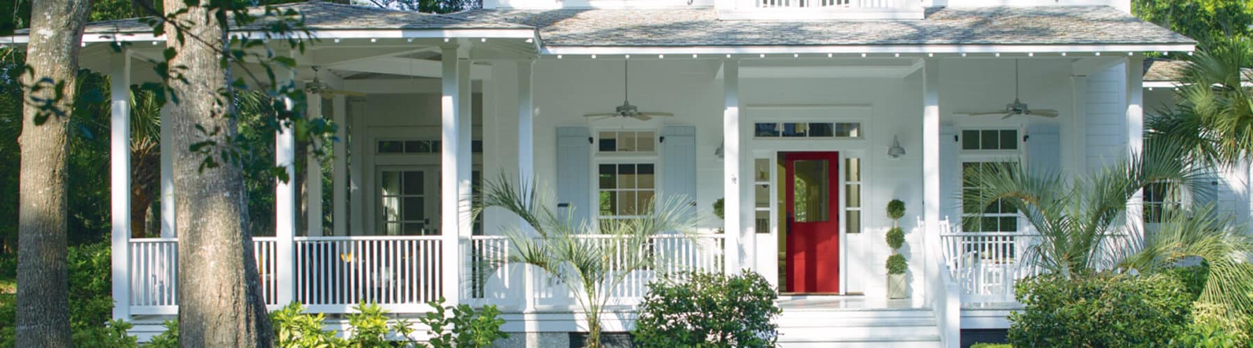 white house with a large farmer's porch and a bright red front door