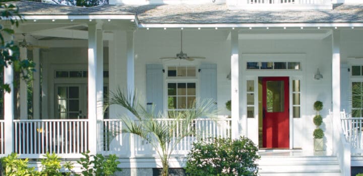 white house with a large farmer's porch and a bright red front door