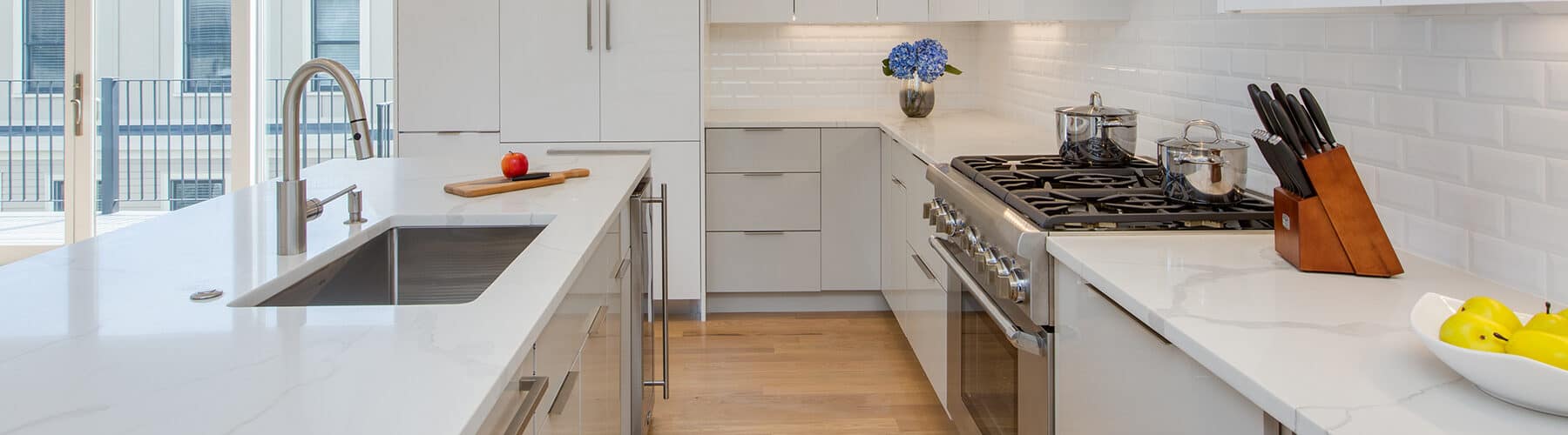 side view of a contemporary white and grey kitchen design with quartz countertops in East Boston, MA