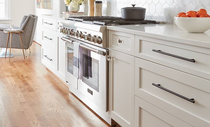 a low side view of base kitchen cabinets with modern style cabinet hardware and a stainless steel stove