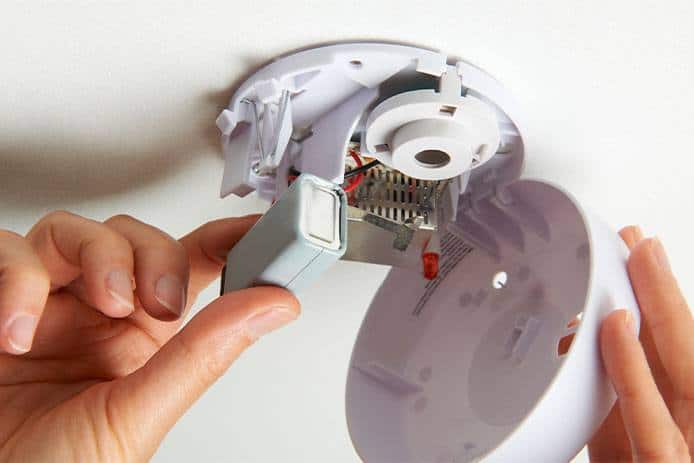 hands changing a smoke alarm battery