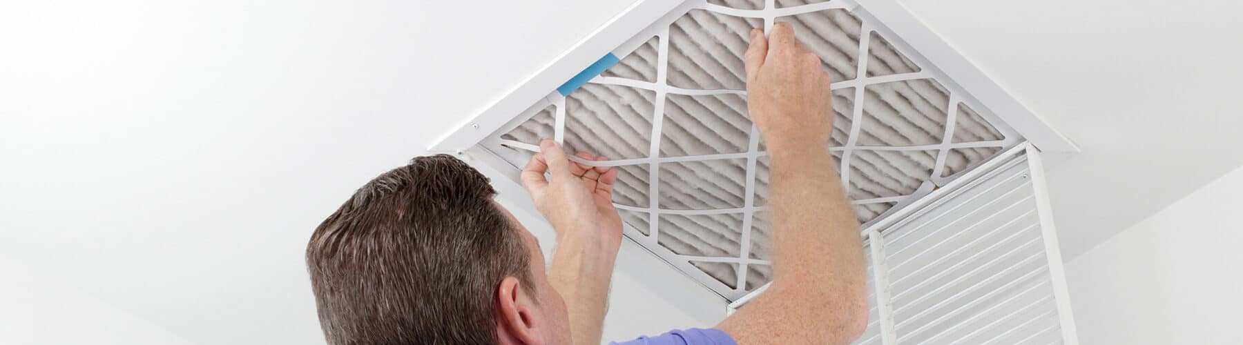 a man changing a ceiling air filter for his furnace