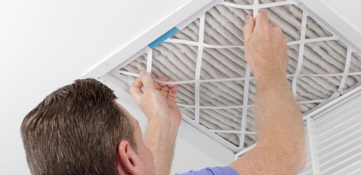 a man changing a ceiling air filter for his furnace